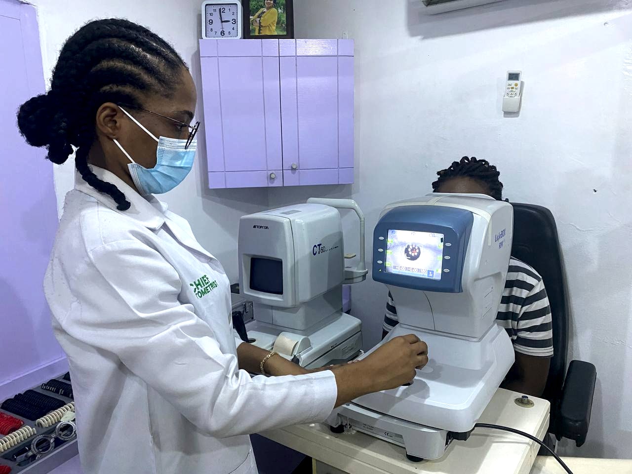 A clinician operating a non-contact tonometer while a patient rests at the chin rest, measuring the pressure inside the eye.